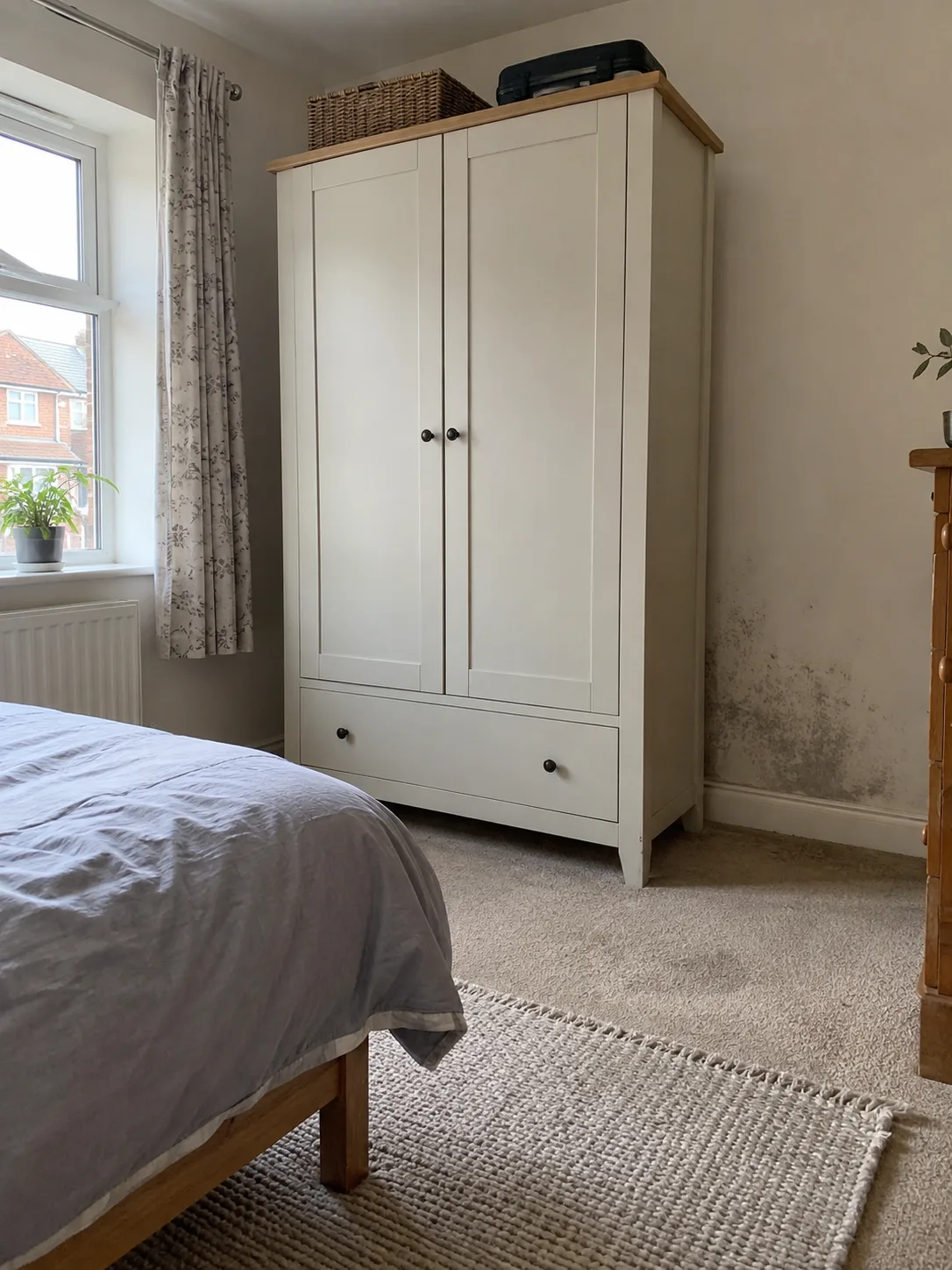 Mould spotting on a bedroom wall beside a wardrobe