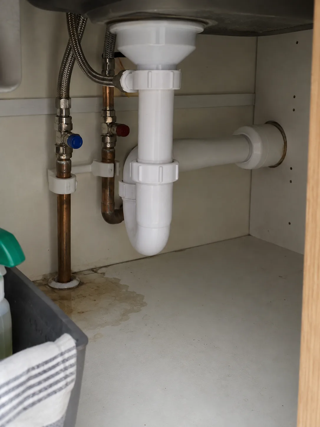 Damp staining below accessible kitchen sink pipework